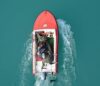 Top view of a red motorboat with fishermen navigating open turquoise waters.